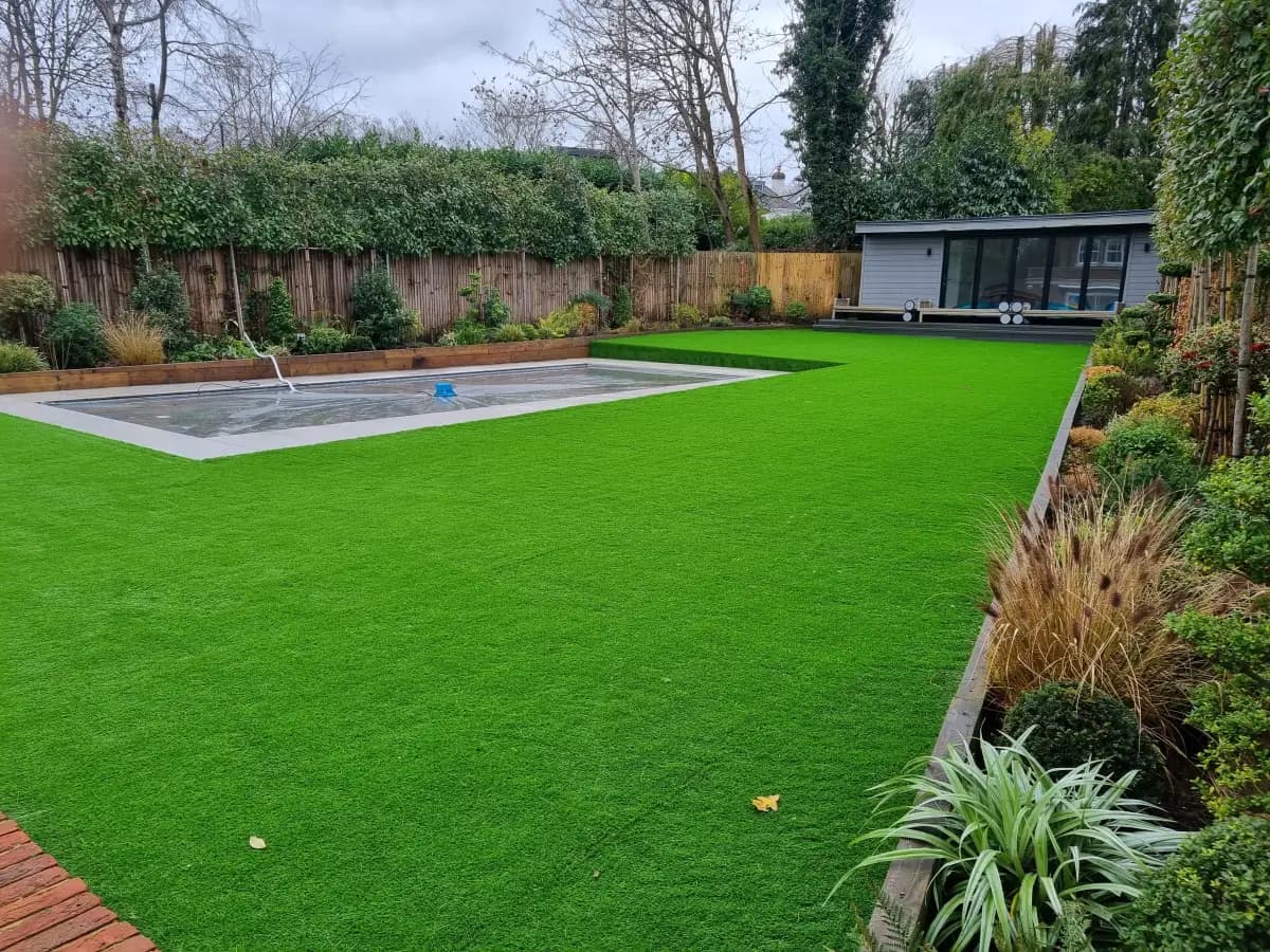 Artificial grass garden beside a pool in Radlett